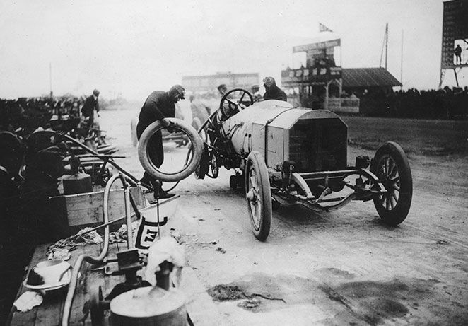 Veteran race car having its wheel changed by three men
