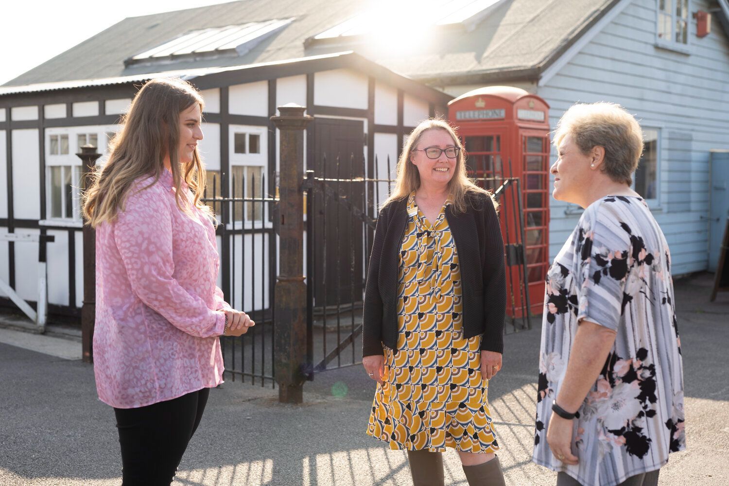 Three women talking outside the old sheds of the motoring village at Brooklands