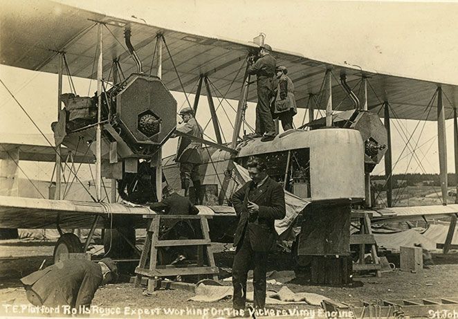 Vintage biplane being built, group of men working on and infront of the aircraft the aircraft